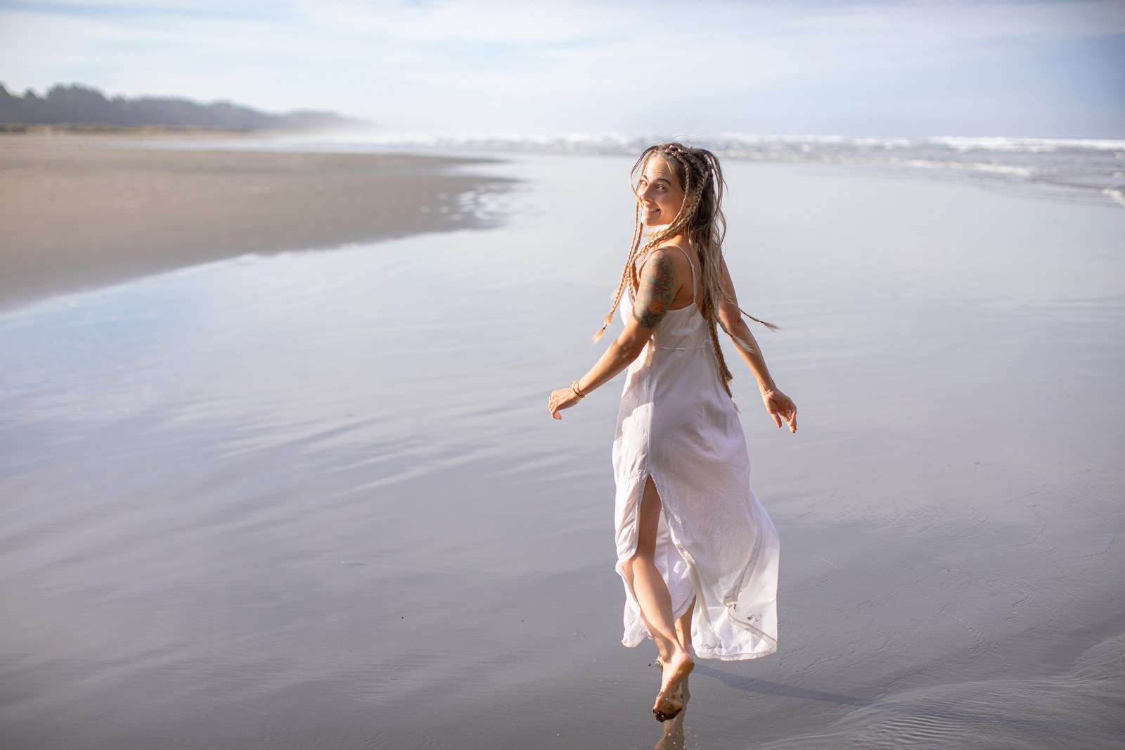 Rachel Naomi walking the shoreline, turning back with a smile